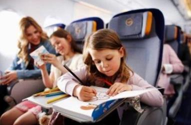 девочка рисует в кресле самолета